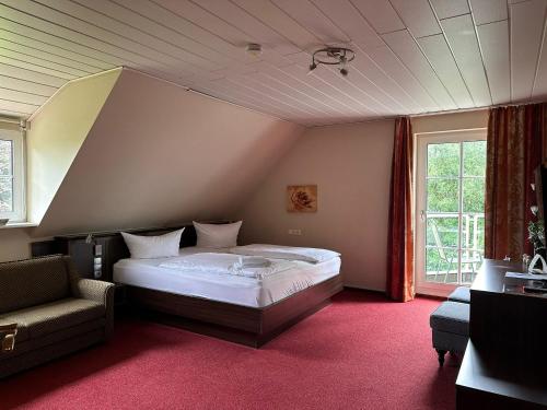 a bedroom with a bed and a chair and a window at Hotel Saltenhof in Hörstel