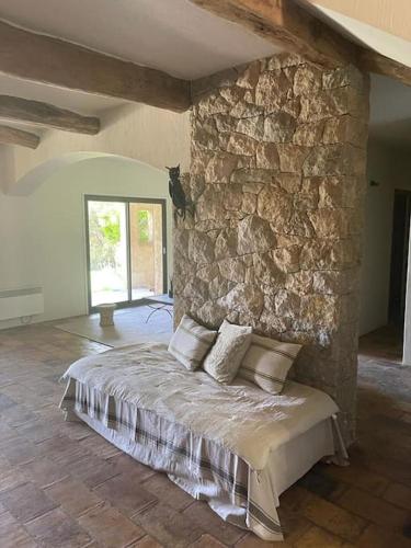 Cette chambre est dotée d'un mur en pierre et d'un lit avec des oreillers. dans l'établissement La Canopée du Loup, à Tourrettes-sur-Loup