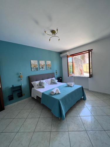 a bedroom with a bed with blue walls and a window at La Noce Holiday House in Massa Lubrense