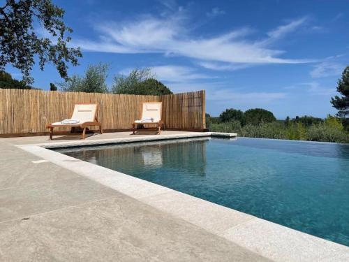 - une piscine avec 2 chaises à côté d'une clôture en bois dans l'établissement La Canopée du Loup, à Tourrettes-sur-Loup