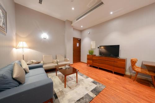 a living room with a blue couch and a flat screen tv at Celine Home Serviced Apartment Al Malqa in Riyadh