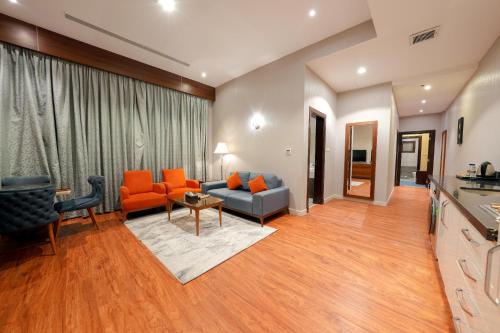 a living room with orange chairs and a couch at Celine Home Serviced Apartment Al Malqa in Riyadh