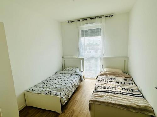 une chambre avec deux lits et une fenêtre dans l'établissement Appartement spacieux et calme 20 min Champs Élysée, à Pierrefitte-sur-Seine