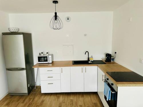  La cuisine est équipée de placards blancs et d'un réfrigérateur. dans l'établissement Appartement spacieux et calme 20 min Champs Élysée, à Pierrefitte-sur-Seine