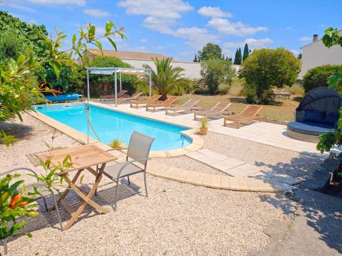 - une piscine avec une table et des chaises à côté dans l'établissement Maison Matisse, à Saint-Nazaire-dʼAude