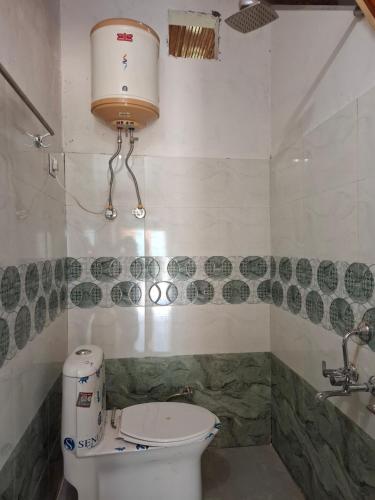 a bathroom with a toilet with a light above it at Paras Homestay in Shoja