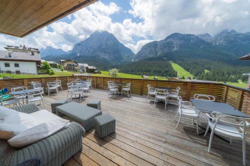 a balcony with chairs and tables and a view of mountains at Bach Boutique Hotel in Sappada