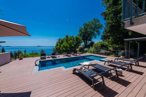 a swimming pool on a wooden deck with chairs at Villa Hortensia-With Private Pool and Beaches Front in Mlini