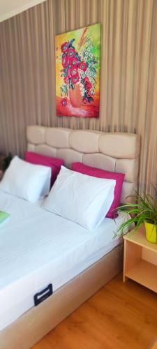 a bed with two pillows and paintings on the wall at Cedar Lodge 3/4 Apartment Paradise in Bansko