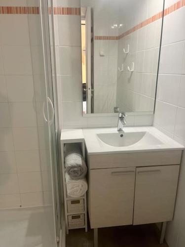 une salle de bain blanche avec un lavabo et un miroir dans l'établissement La plagiste, à Saint-Palais-sur-Mer
