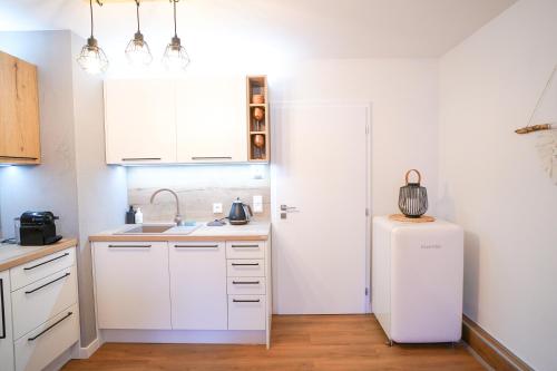 a kitchen with white cabinets and a refrigerator at Útulný apartmán St Michael v Javorné na Šumavě in Čachrov