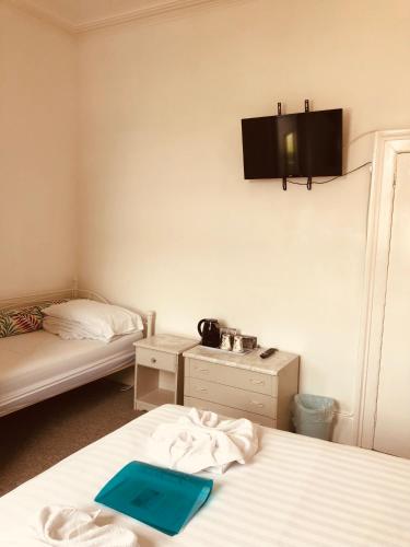 a room with two beds and a tv on the wall at The Purple Tree Guest House in Torquay