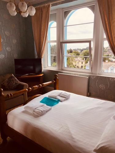 a bedroom with a large bed with a window at The Purple Tree Guest House in Torquay