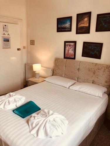 a bedroom with a bed with towels on it at The Purple Tree Guest House in Torquay