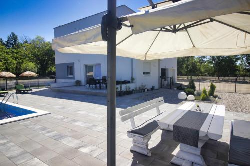 un patio con mesa, sombrilla y piscina en Apartment - CASA Adrianovo, en Ljubuški