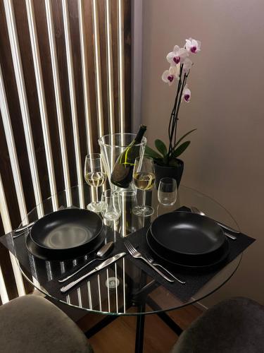 a glass table with black plates and wine glasses at Renard Suite in Cefalù