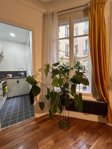 un salon avec une grande fenêtre et une plante dans l'établissement Havre de paix à Paris, à Paris