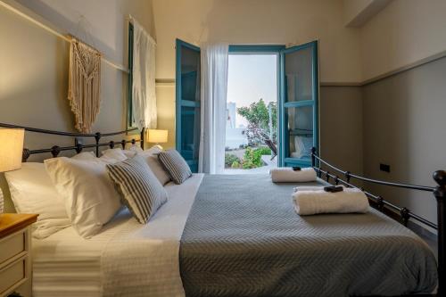 Un dormitorio con una cama grande con una ventana grande. en Adagio Villas Kamari, en Kamari