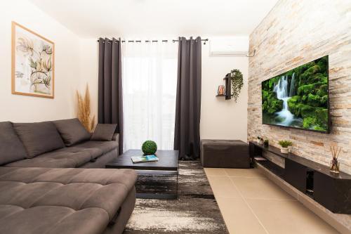 een woonkamer met een bank en een tv aan een bakstenen muur bij New Apartment in Vrnjačka Banja