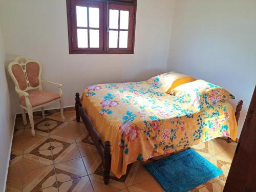a bedroom with a bed and a chair and a window at Studio de charme à Bouillante, 100 m², vue sur mer et montagnes in Bouillante