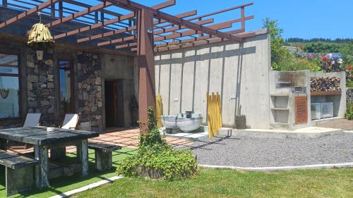 a patio with a table and a wooden pergola at Villa - Cantinho do Paraíso in Santo Espírito
