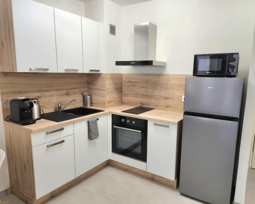  La cuisine est équipée de placards blancs et d'un réfrigérateur. dans l'établissement Le Cassidain - Port et plage - Luxious appartement, à Cassis