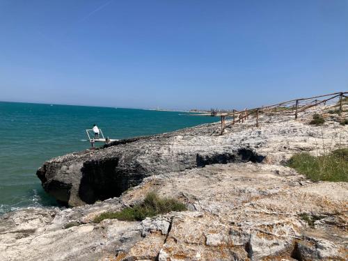 a man sitting on a chair on a rock formation in the ocean at Hesperia case vacanze in Vieste