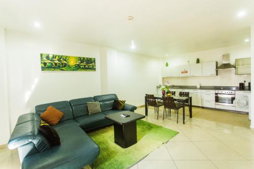 a living room with a blue couch and a kitchen at Accra Luxury Apartments at Clifton Place in East Legon