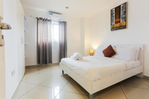 a white bedroom with a bed and a window at Accra Luxury Apartments at Clifton Place in East Legon