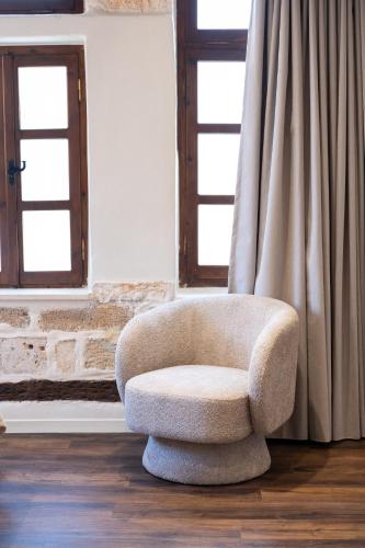 a chair sitting in a room with two windows at Qualia Slowlife Suites in Chania Town