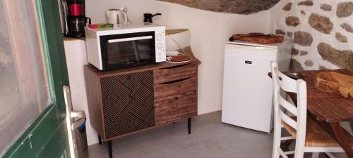 a microwave sitting on top of a wooden stand in a kitchen at ZACHAROULA ROOMS 2 in Manganítis