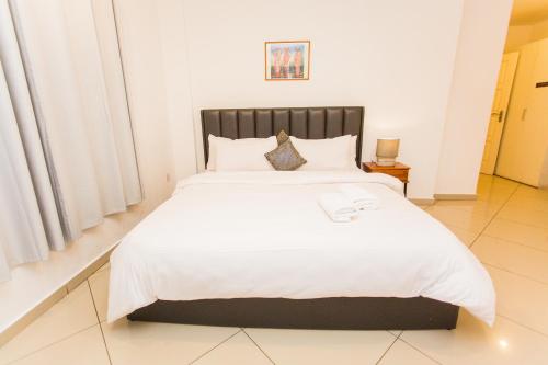 a bedroom with a large bed with white sheets at Accra Luxury Apartments at Clifton Place in East Legon