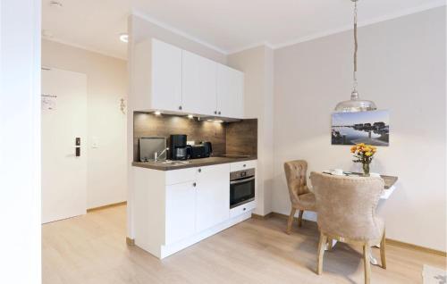 a kitchen with white cabinets and a table and chairs at Baltischer Hof Apartment 23 in Boltenhagen