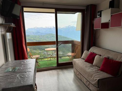 a living room with a couch and a large window at Studio montagne in Villarembert