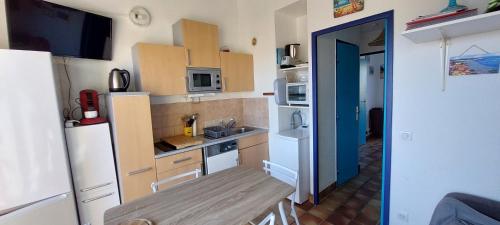 une petite cuisine avec une table et un réfrigérateur dans l'établissement Argelès 50 m plage, vue mer, à Argelès-sur-Mer