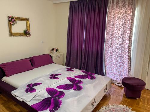 a bedroom with a bed with purple curtains and a window at Villa Kraljevski in Kumanovo