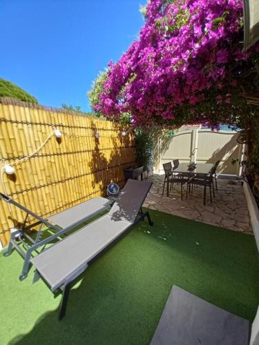 un patio avec un banc et une table avec des fleurs violettes dans l'établissement Studio avec rez de jardin, à Six-Fours-les-Plages