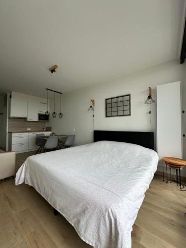 een slaapkamer met een groot wit bed en een keuken bij Work or holiday nieuw studio Santhooft in Nieuwpoort