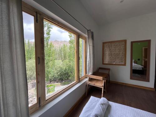 a bedroom with a large window and a chair at THE KOI STAY in Leh