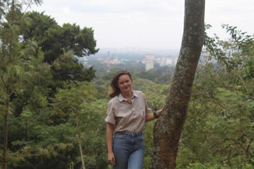 a woman is standing next to a tree at Kilimani gardens hostel in Arusha