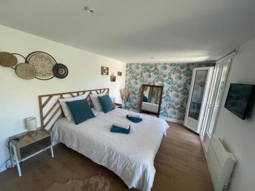 a bedroom with a large white bed with blue pillows at Pavillon T2 climatisé in Villefranche-de-Lauragais