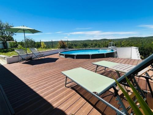 une terrasse avec une piscine, une table et un parasol dans l'établissement La Bruyère, à Rochefort-du-Gard