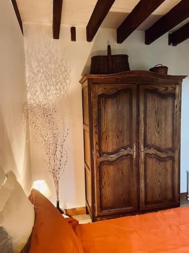 une grande armoire en bois dans une chambre avec un canapé dans l'établissement Le gîte des filles en bottes, à Saint-Georges-de-Reintembault