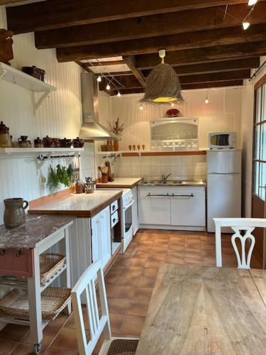 une cuisine avec des appareils blancs et un parquet dans l'établissement Le gîte des filles en bottes, à Saint-Georges-de-Reintembault