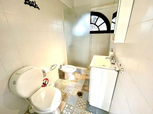 a white bathroom with a toilet and a sink at Bobi’s House in Chacras de Coria