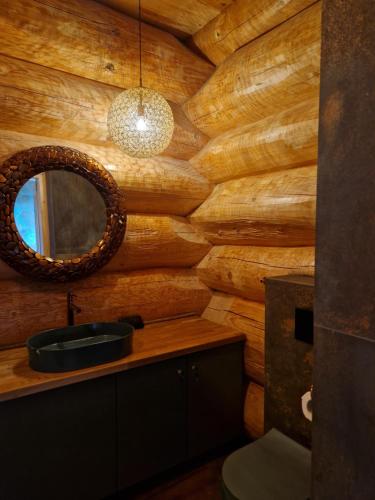a bathroom with a wooden wall with a mirror and a sink at Chata Braci Warchały in Warchały