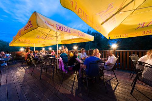 un grupo de personas sentadas en mesas en una terraza por la noche en Hotel s restaurací Splávek, en Strakonice