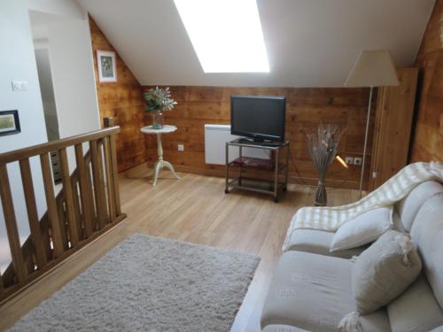 un salon avec un canapé et une télévision dans l'établissement La Glycine, à Le Bardon