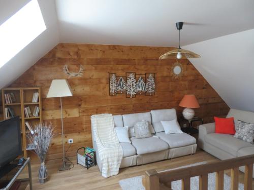 - un salon avec un canapé blanc et un mur en bois dans l'établissement La Glycine, à Le Bardon