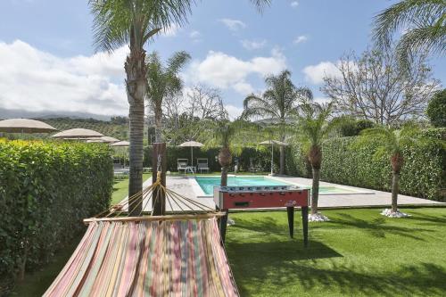 a hammock in a yard with a pool and palm trees at Le Zagare in Lascari